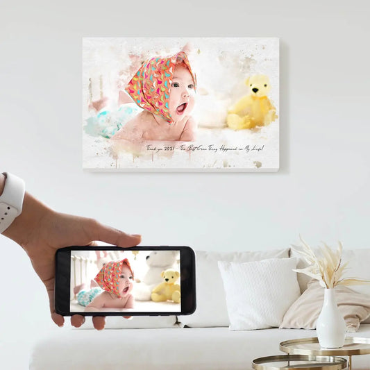 A custom watercolor portrait canvas featuring a smiling baby in a colorful headscarf next to a yellow teddy bear, displayed on a bright living room wall above a white couch. Free shipping by Incotta.