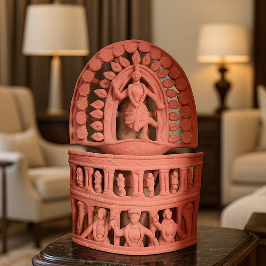 A lifestyle photograph showcasing the intricate handcrafted terracotta temple relief sculpture displayed as a centerpiece on a dark polished table. The image features a warm, sophisticated living room background with soft lighting, highlighting the traditional Indian craftsmanship and detailed openwork design.