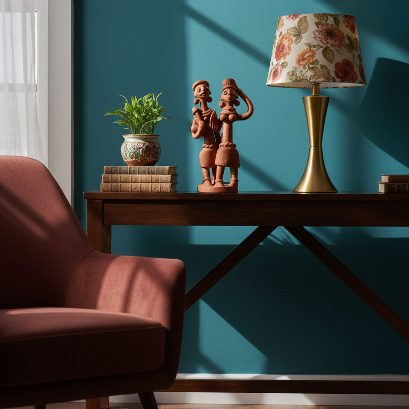 Ethnic Indian terracotta couple figurine on a console table, paired with indoor plant and decorative lamp for warm living room decor styling.