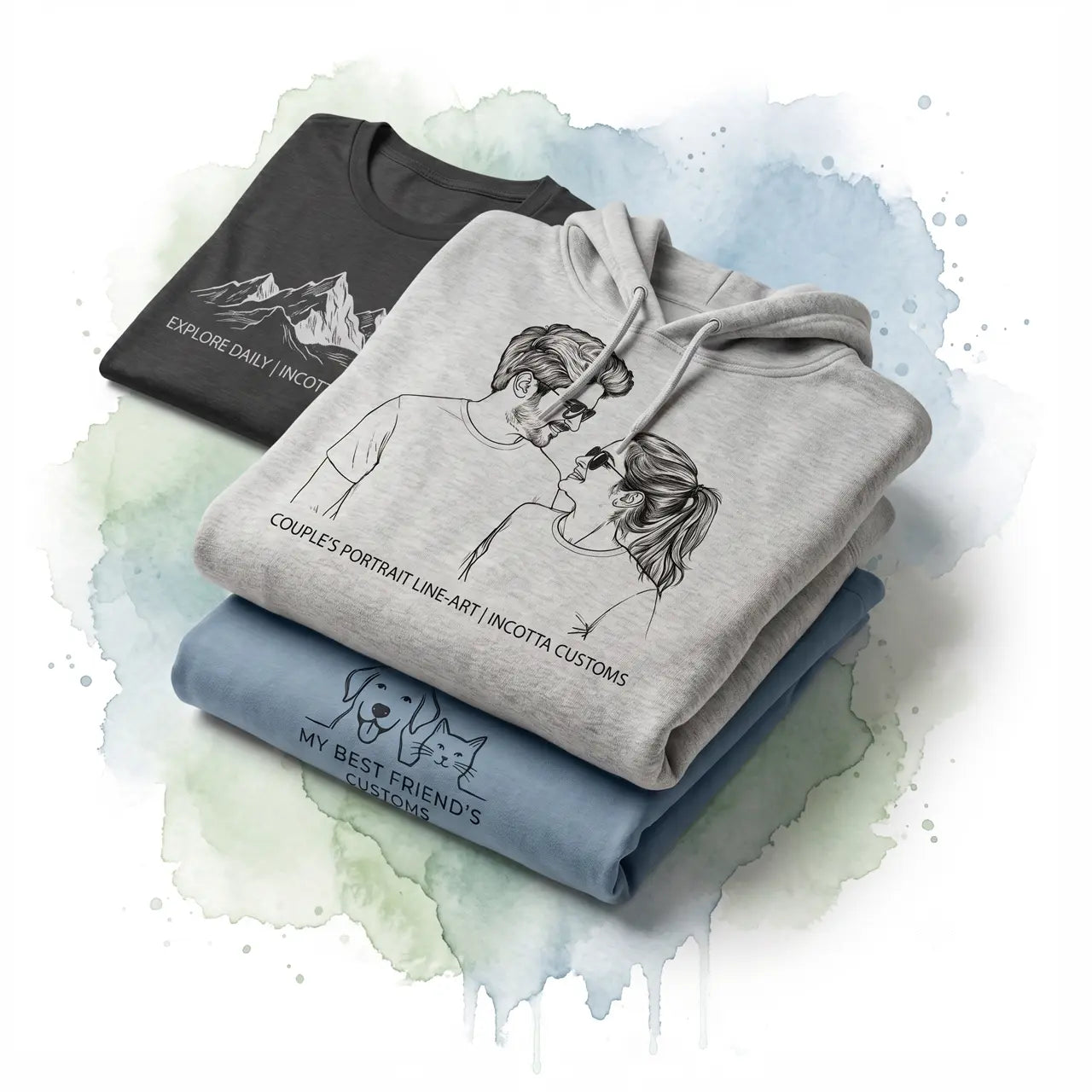 Stacked custom graphic apparel featuring a couple's line art hoodie, mountain t-shirt, and pet shirt on watercolor.