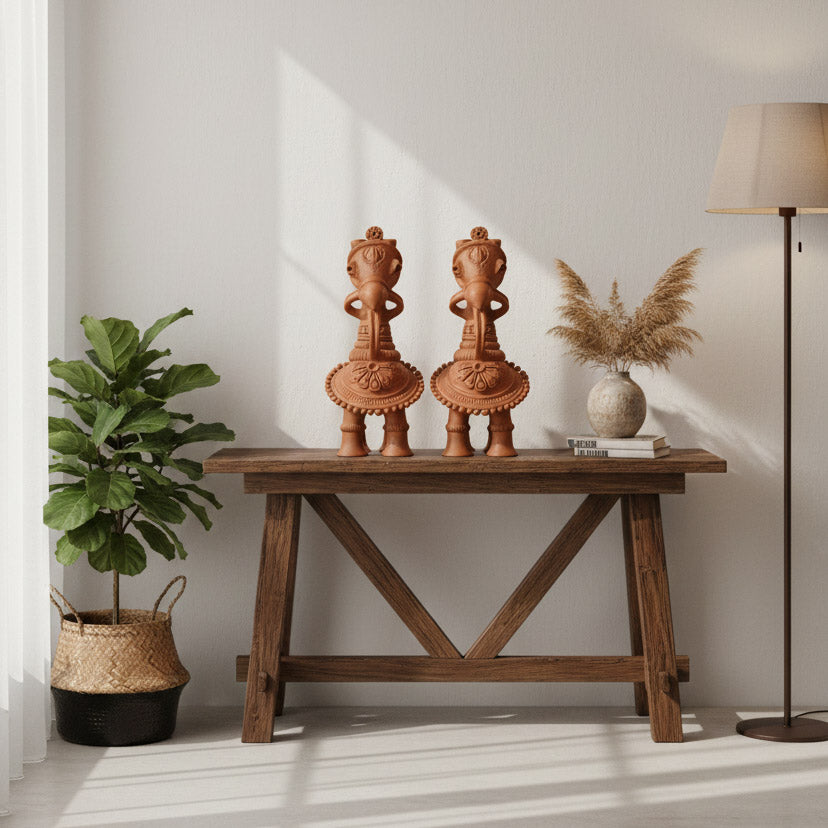 Handmade terracotta horse decor sculptures styled on a wooden table with plant and floor lamp for home interior styling.