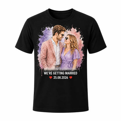 A light black unisex t-shirt featuring a custom pastel watercolor portrait of an engaged couple in sunglasses, with We're Getting Married text and a wedding date. Free shipping by Incotta.