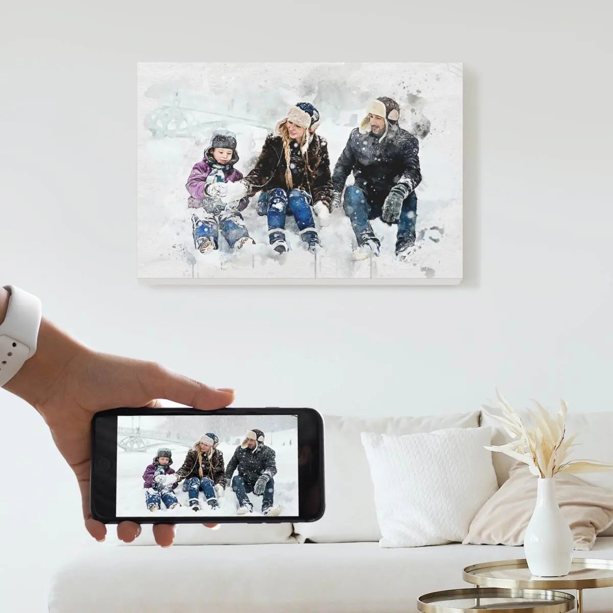 A custom watercolor portrait canvas featuring a family of three sitting in the snow, displayed on a bright living room wall above a white couch. Free shipping by Incotta.