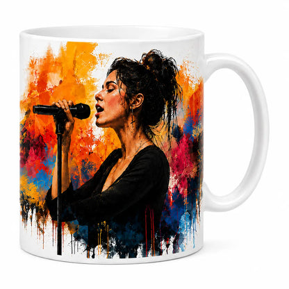 A glossy white ceramic coffee mug featuring a vibrant custom watercolor portrait of a female singer at a microphone, surrounded by colorful orange, blue, and pink splatters. Free shipping by Incotta.