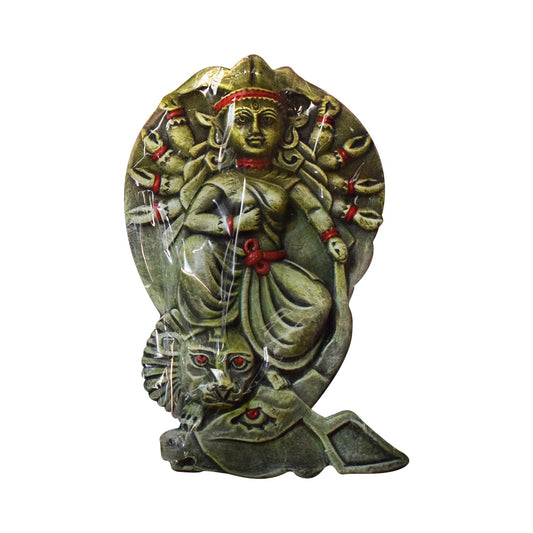 An angled view of a handcrafted terracotta wall hanging depicting Goddess Durga seated on her lion mount. This clay relief sculpture highlights the depth of the ten-armed deity figure and the intricate texture of the lion, featuring a rustic greenish-grey finish with vibrant red hand-painted accents.