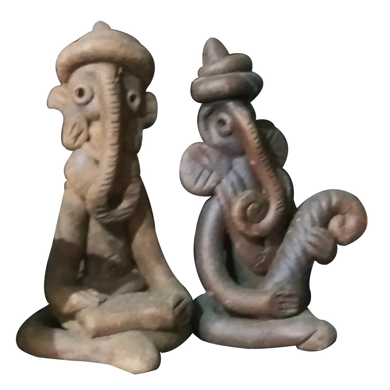 A studio shot featuring a pair of handcrafted terracotta figurines depicting stylized Lord Ganesha. The set includes two seated idols, one in a meditative posture and the other playing a curved musical instrument, showcasing traditional tribal design and earthen clay textures isolated against a white background.