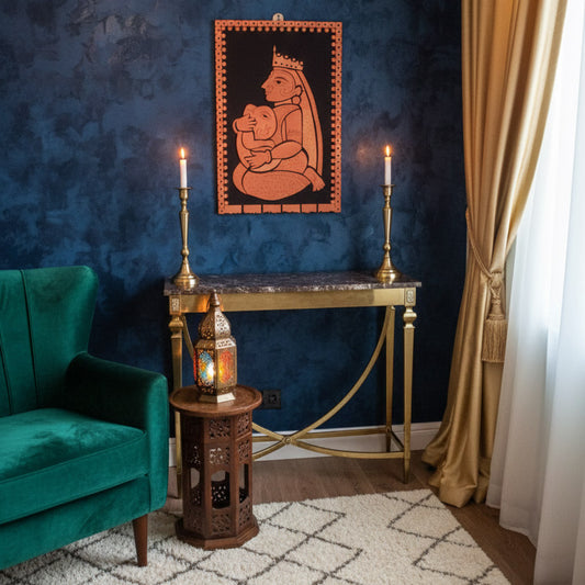 Handcrafted terracotta folk art wall panel of a durga holding her ganesh, displayed in an elegant interior with brass accents and ambient candle lighting.