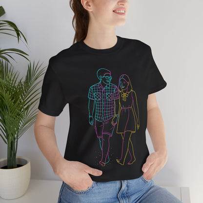 Flat lay of black t-shirt featuring custom neon line art of a couple walking, graphic tee product photography.