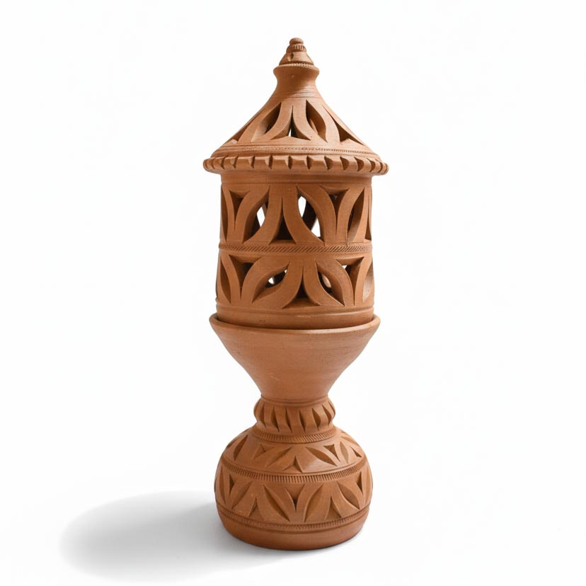 A vertical studio shot of a handcrafted terracotta lantern featuring intricate leaf-shaped cutouts on the body and base. The earthen lamp includes a matching conical lid with a finial, displayed against a clean white background.