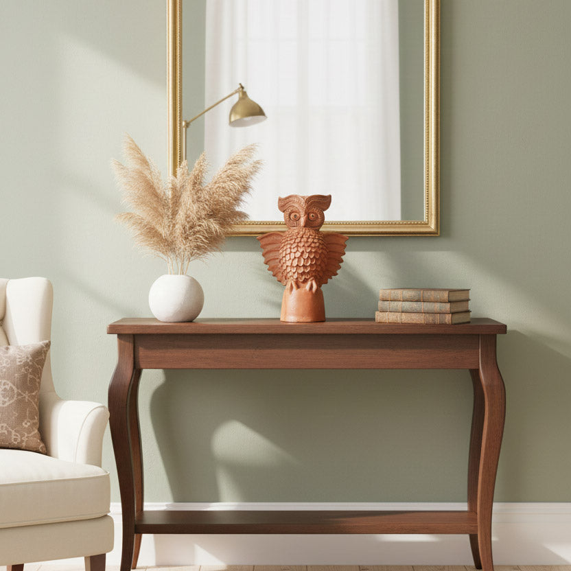 Handmade terracotta owl decor sculpture styled with mirror and wooden furniture for contemporary home interior styling.