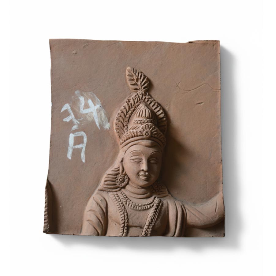 Handcrafted Indian terracotta wall sculpture featuring a deity portrait, rustic spiritual decor panel