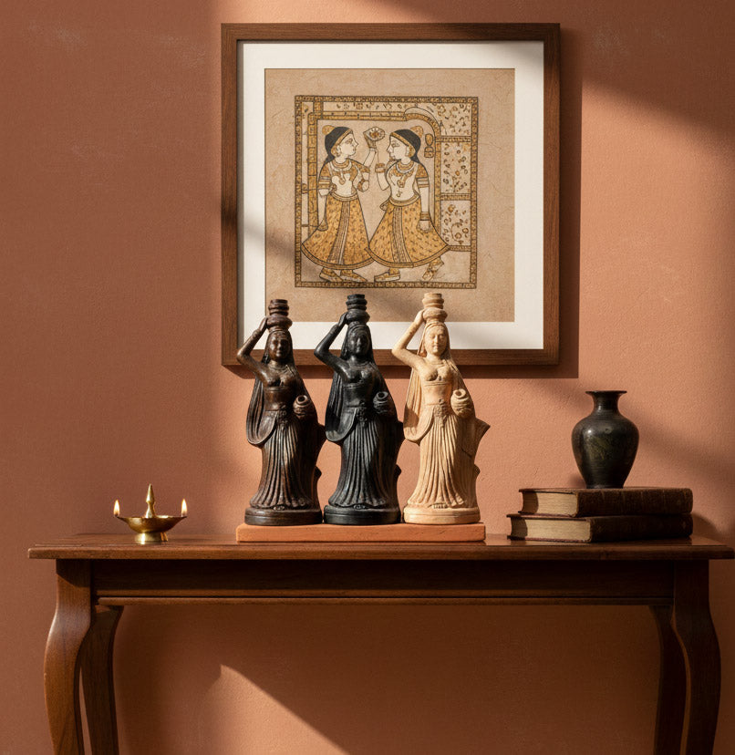 Indian handicraft three woman figurines in terracotta-style finish styled as elegant ethnic decor in a warm interior setting.